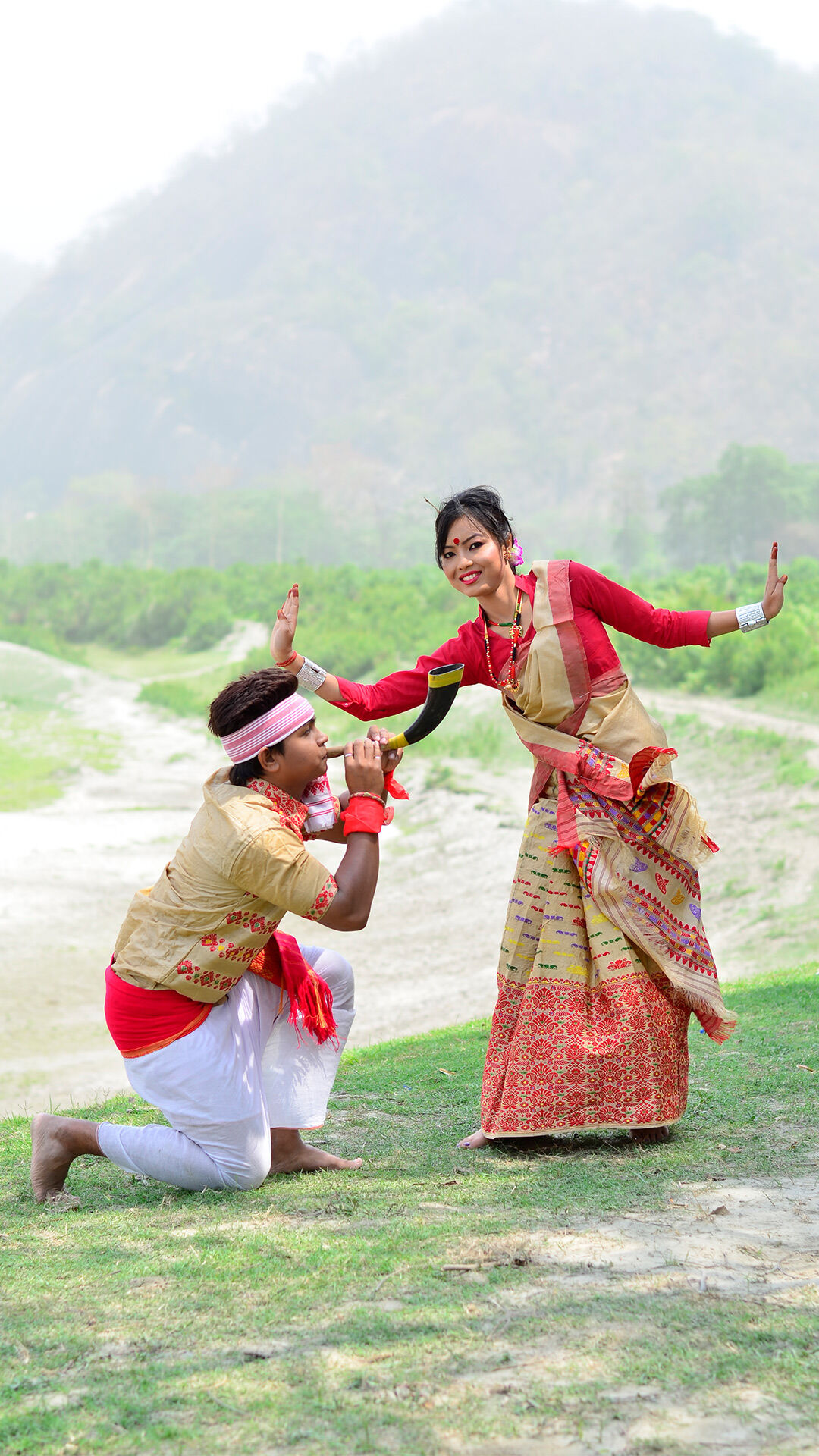 Man performing traditional Bihu ritual dance alongside woman during Bohag Bihu