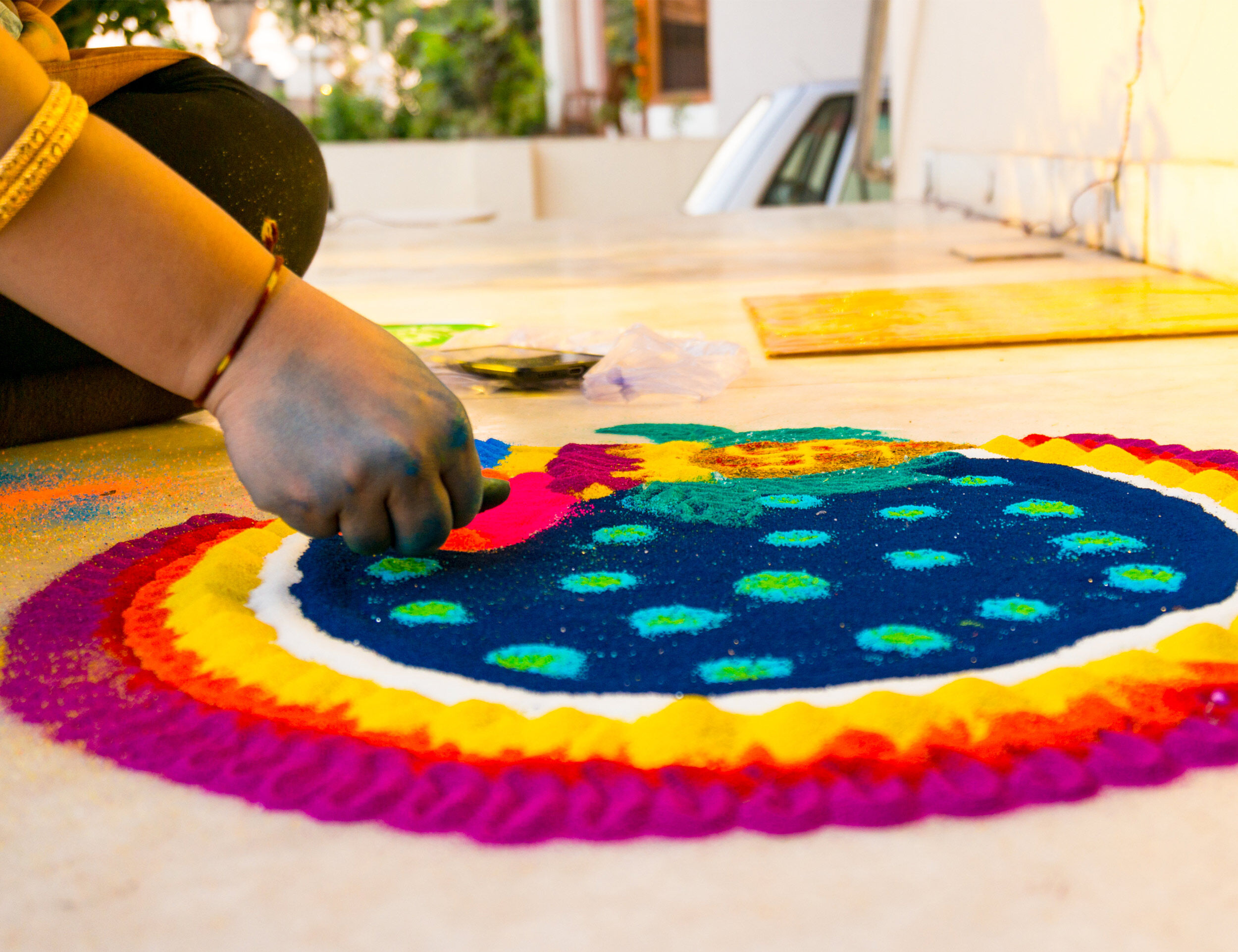 A women creating beatifull colourfull rangoli for holi celebration