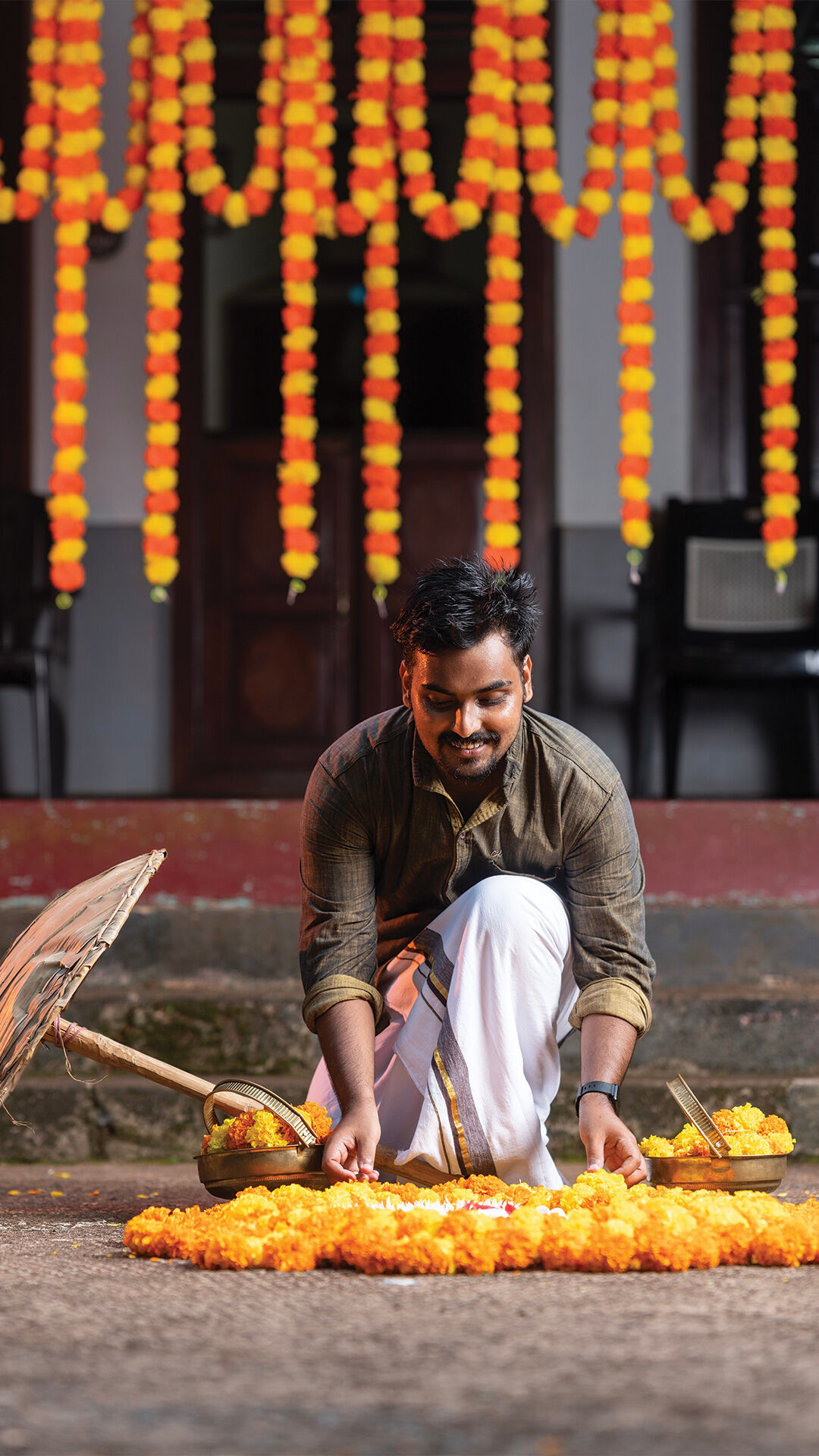 A man in tradition attire applyinbg Marigolds for Pongal decor