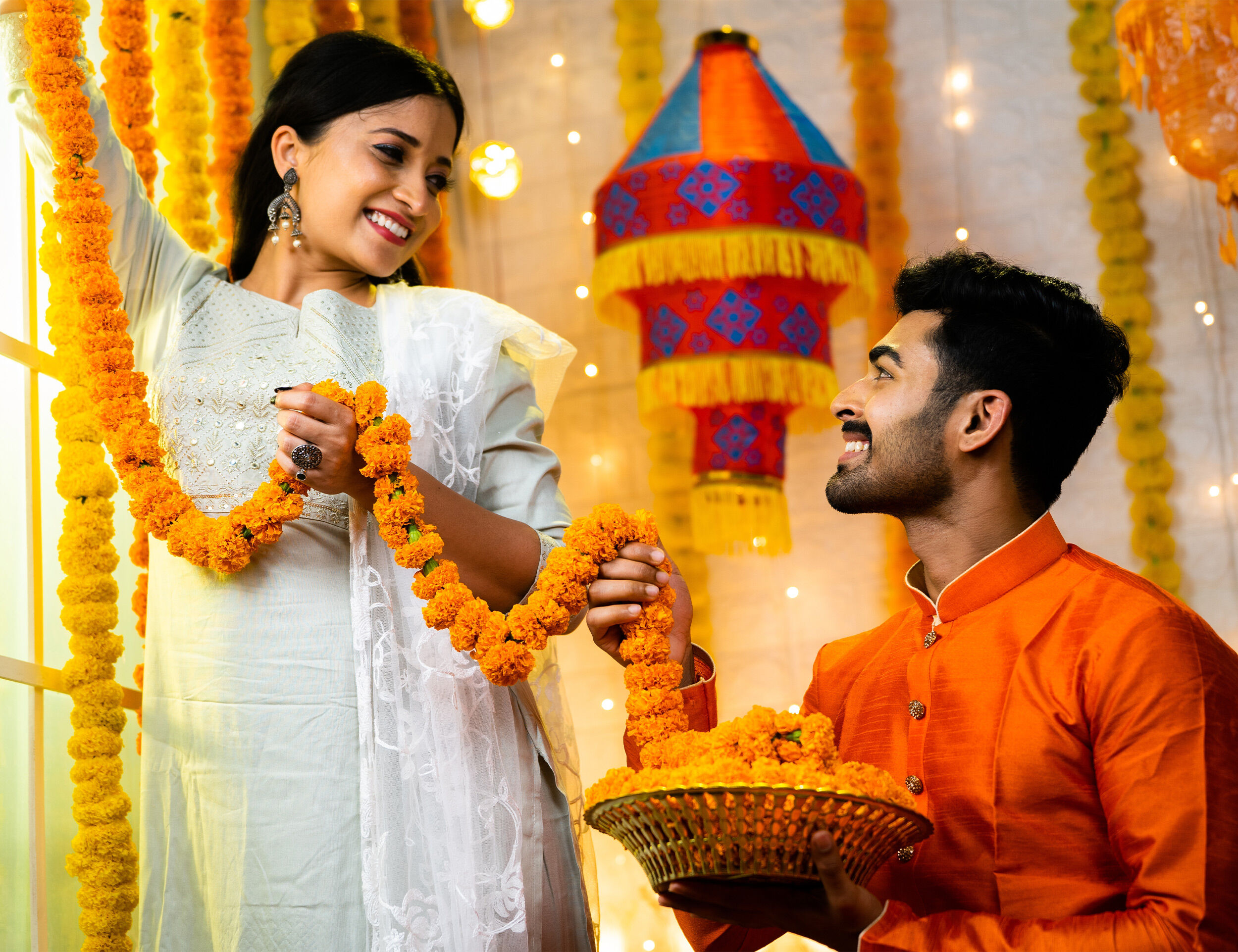 A couple applying yellow flowers mala on wall for fesitival decoration