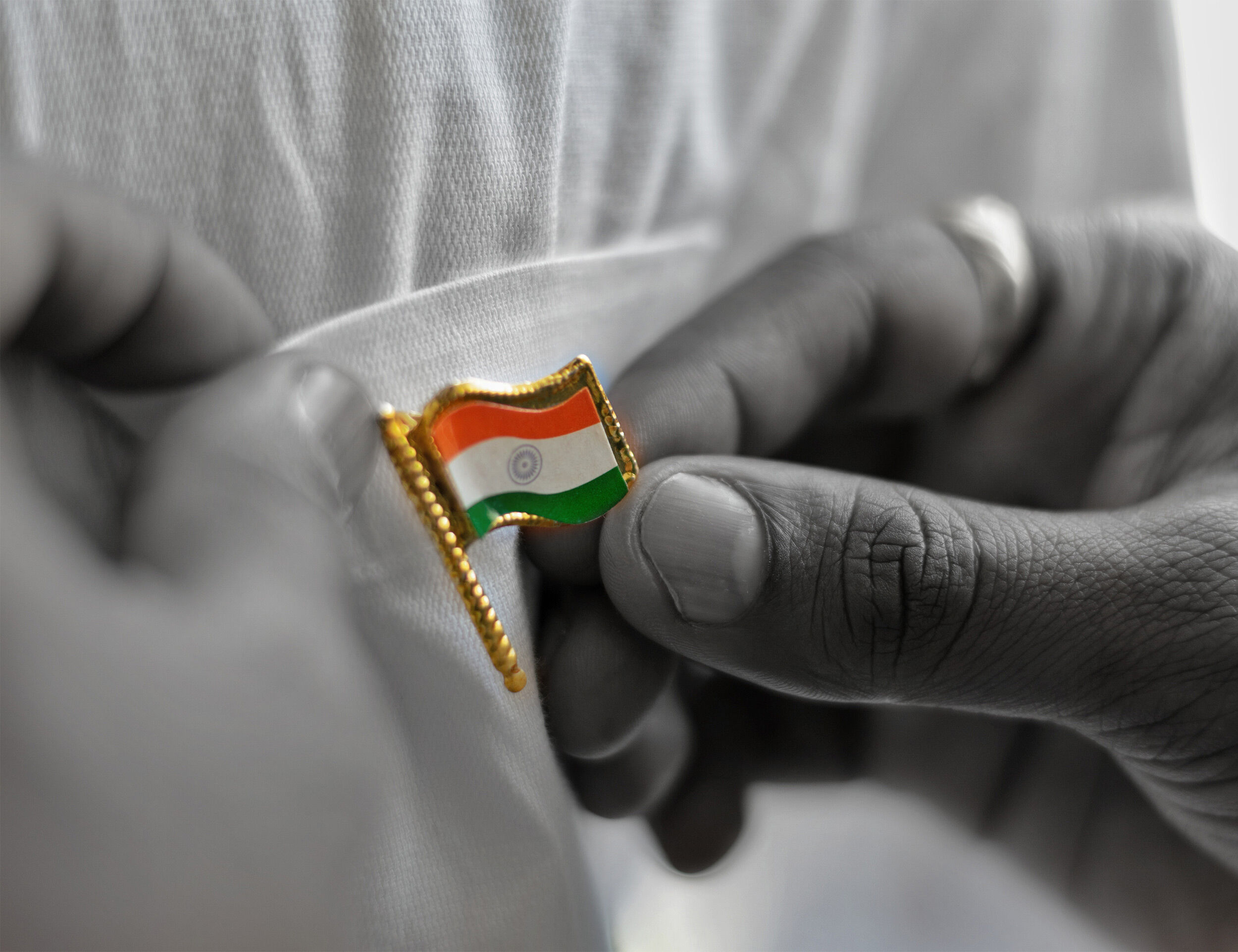 A man sticking a inidan national flag on his shirt pocket on republic day 