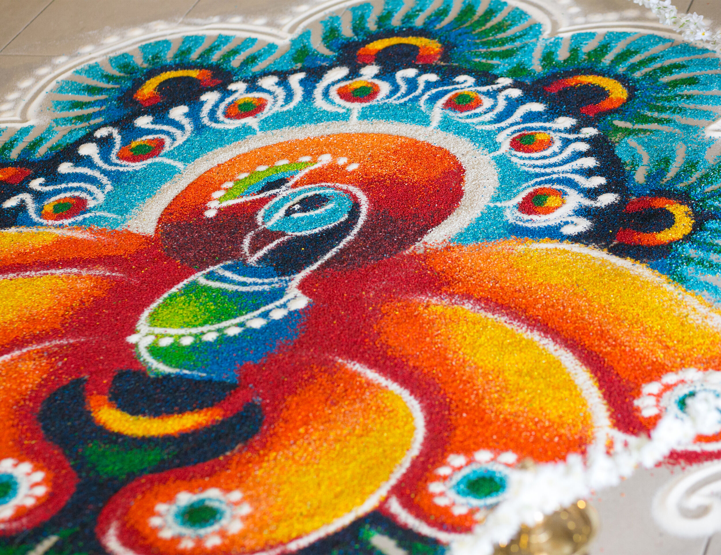 Vibrant peacock-themed Ugadi rangoli design created with colorful sand, featuring intricate patterns and bright hues.