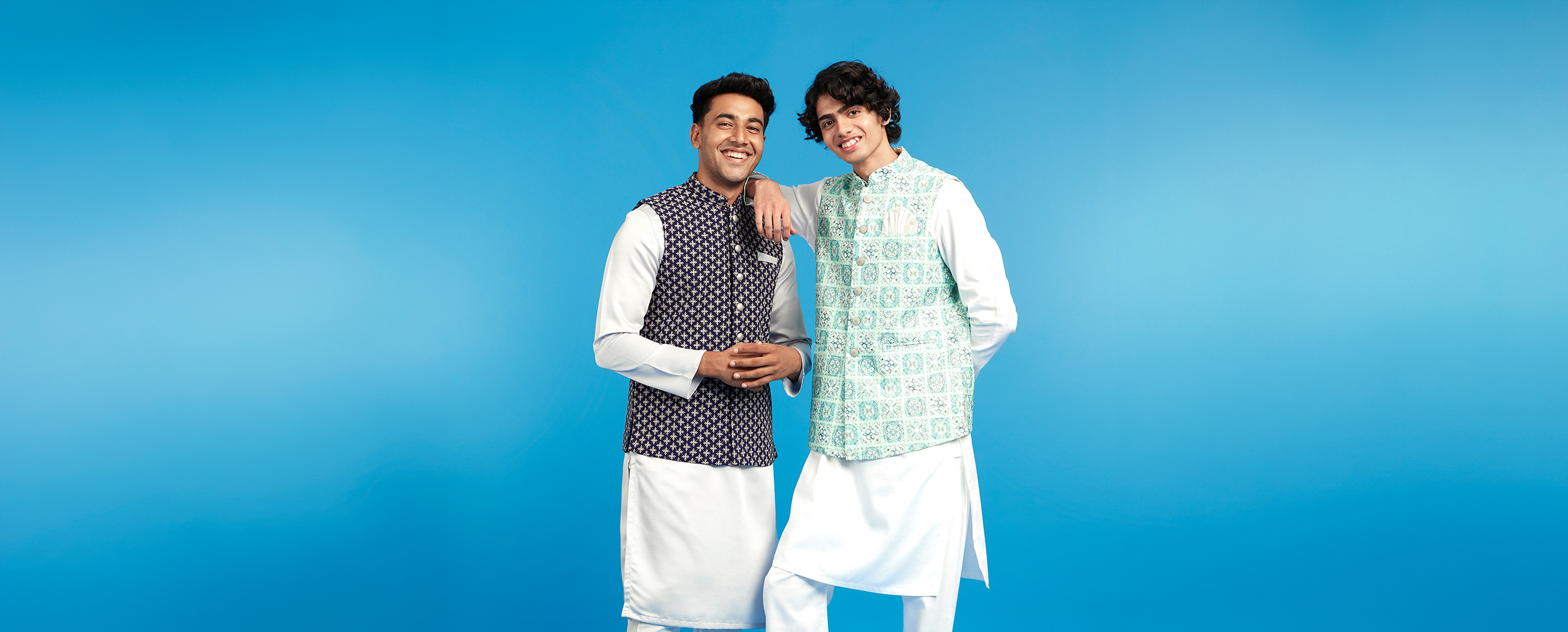 Two men wearing white kurtas layered with printed Nehru jackets, showcasing elegant styling combinations from Diwas' kurta layering guide.
