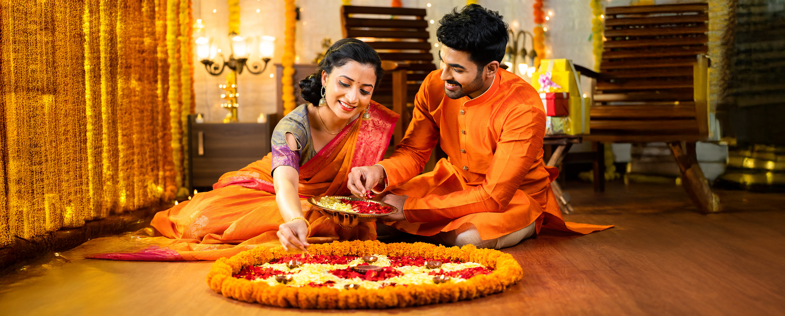 A couple applying flower rangoli for indian festival A couple applying flower rangoli for indian festival