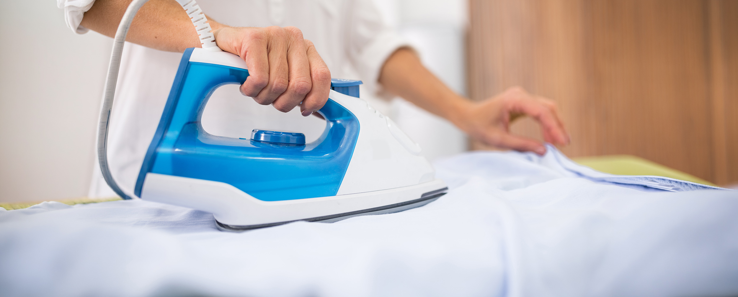 Steam iron being used on a white kurta, highlighting kurta ironing and fabric care tips.
