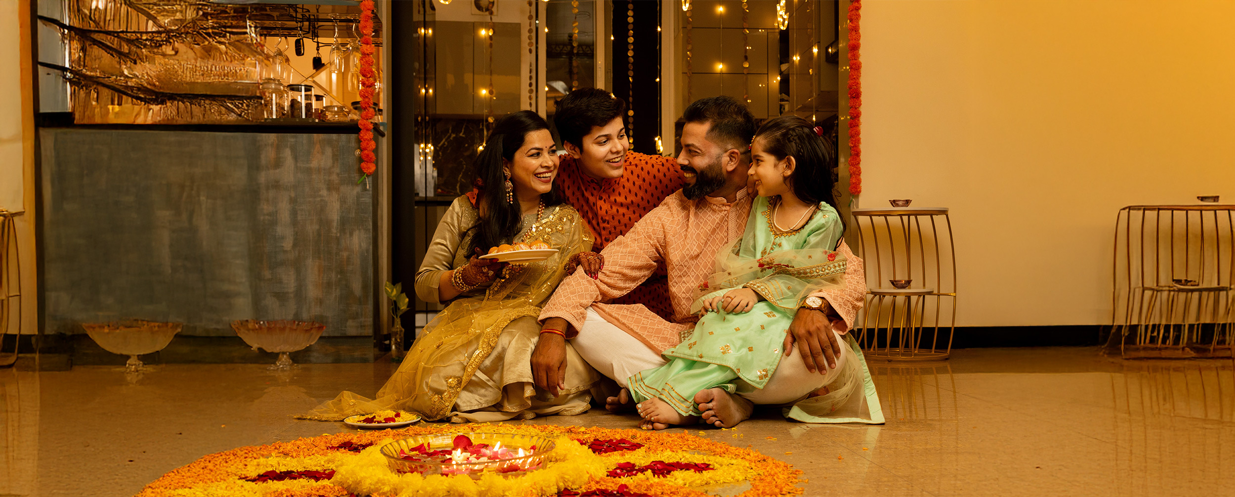 Family enjoying festivals with flowers rangoli and mithais Family enjoying festivals with flowers rangoli and mithais