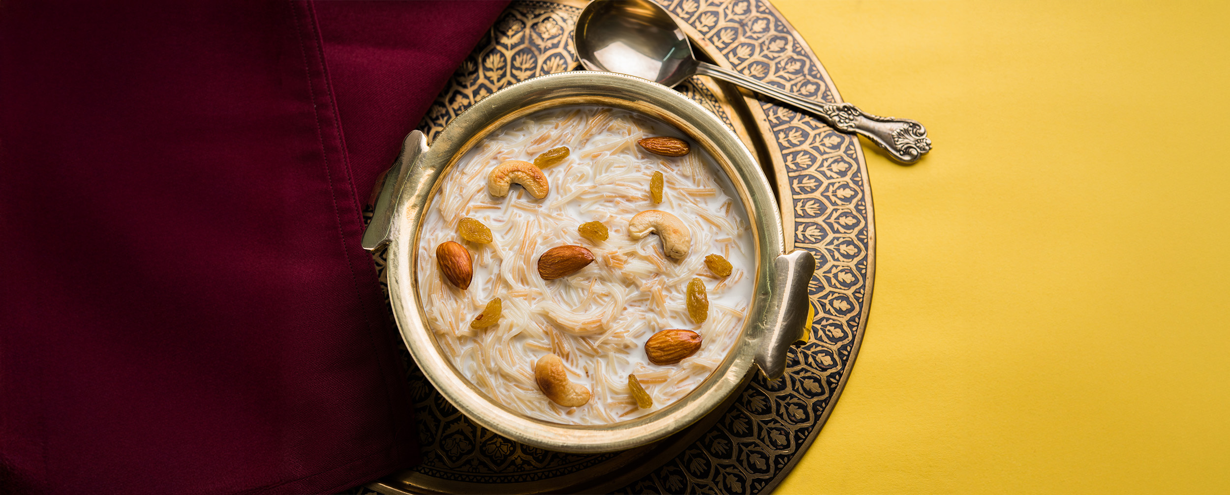 A bowl of Sheer Khurma, a traditional Eid dessert made with vermicelli, milk, and nuts, served in an ornate dish A bowl of Sheer Khurma, a traditional Eid dessert made with vermicelli, milk, and nuts, served in an ornate dish