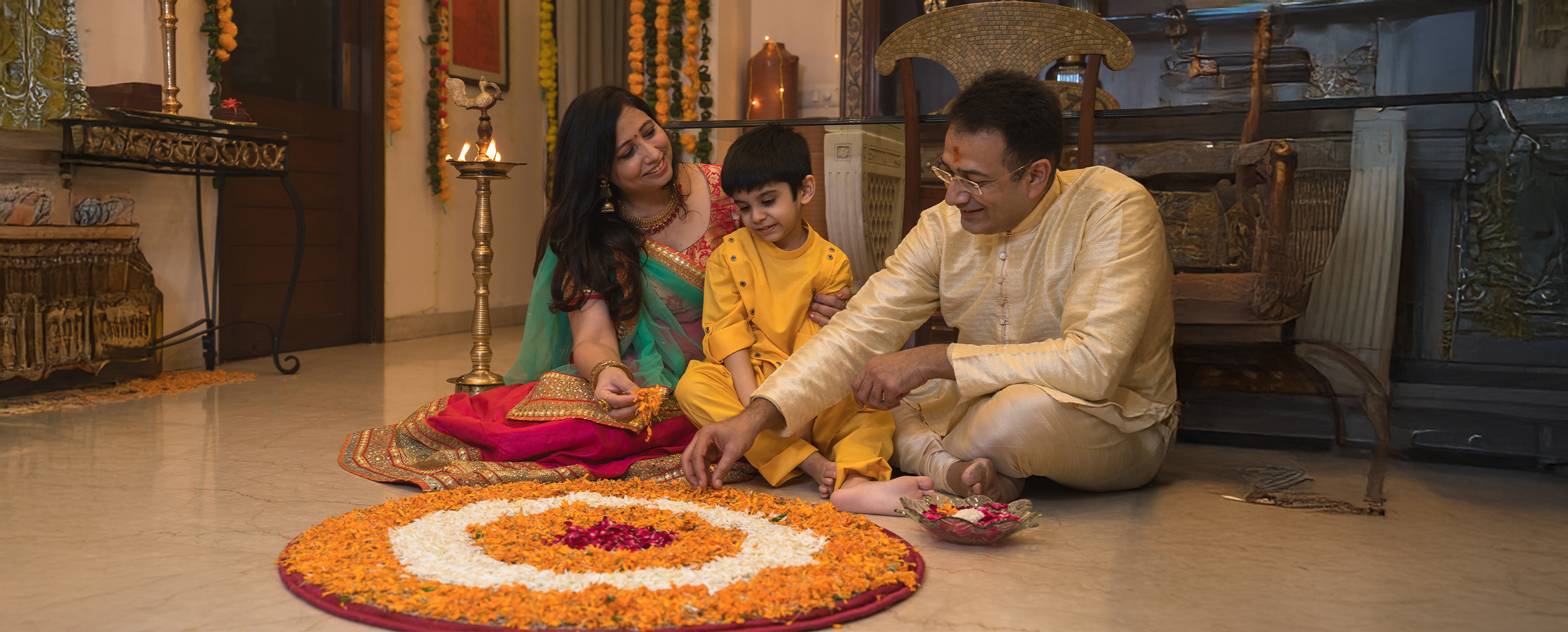 A family applying flowers rangoli on floor for basant panchami celebration A family applying flowers rangoli on floor for basant panchami celebration
