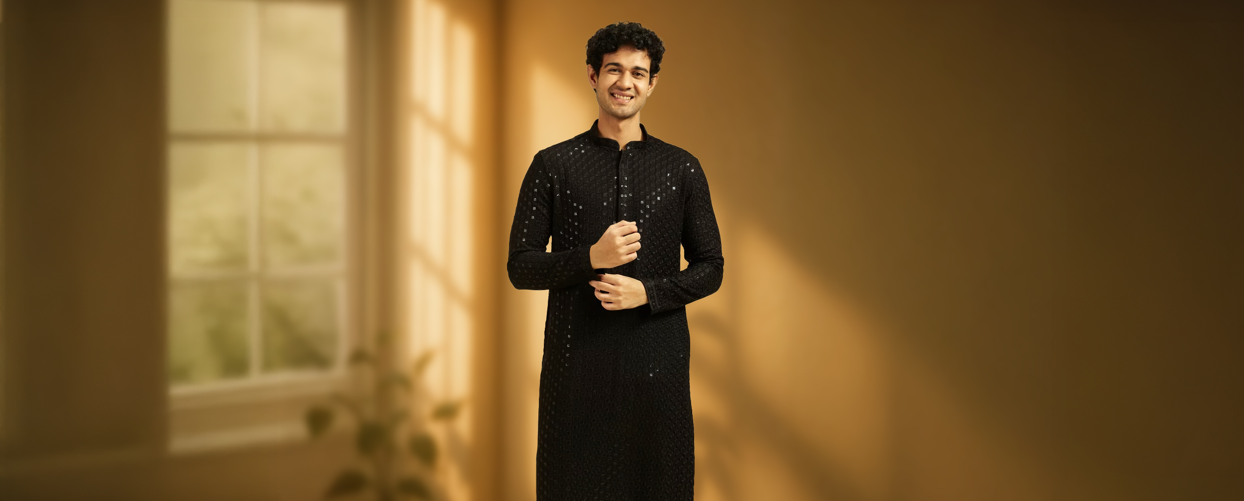 A smiling man wearing a dapper black Chikankari kurta with intricate embroidery. A smiling man wearing a dapper black Chikankari kurta with intricate embroidery.