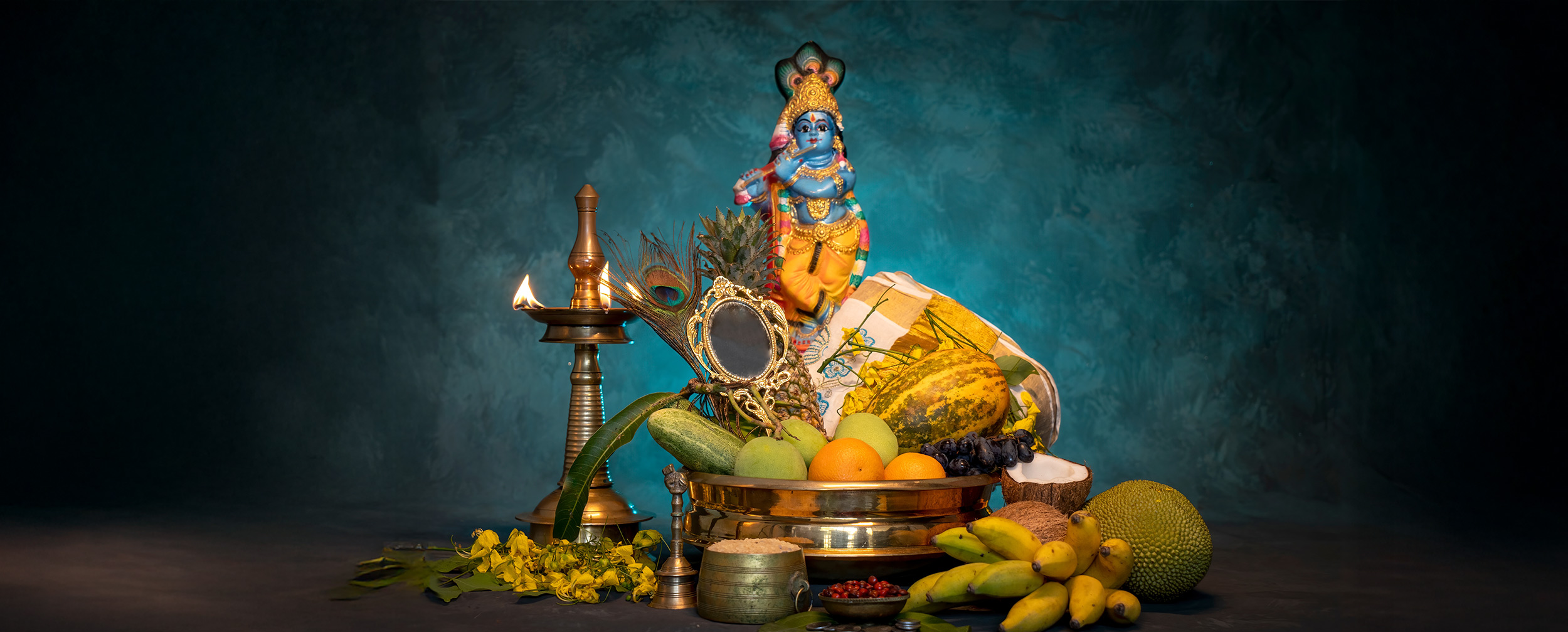 Traditional Vishu Kani arrangement featuring fruits, mirror, lamp, and a statue of Lord Krishna, symbolizing prosperity and blessings during Kerala’s Vishu festival. Traditional Vishu Kani arrangement featuring fruits, mirror, lamp, and a statue of Lord Krishna, symbolizing prosperity and blessings during Kerala’s Vishu festival.