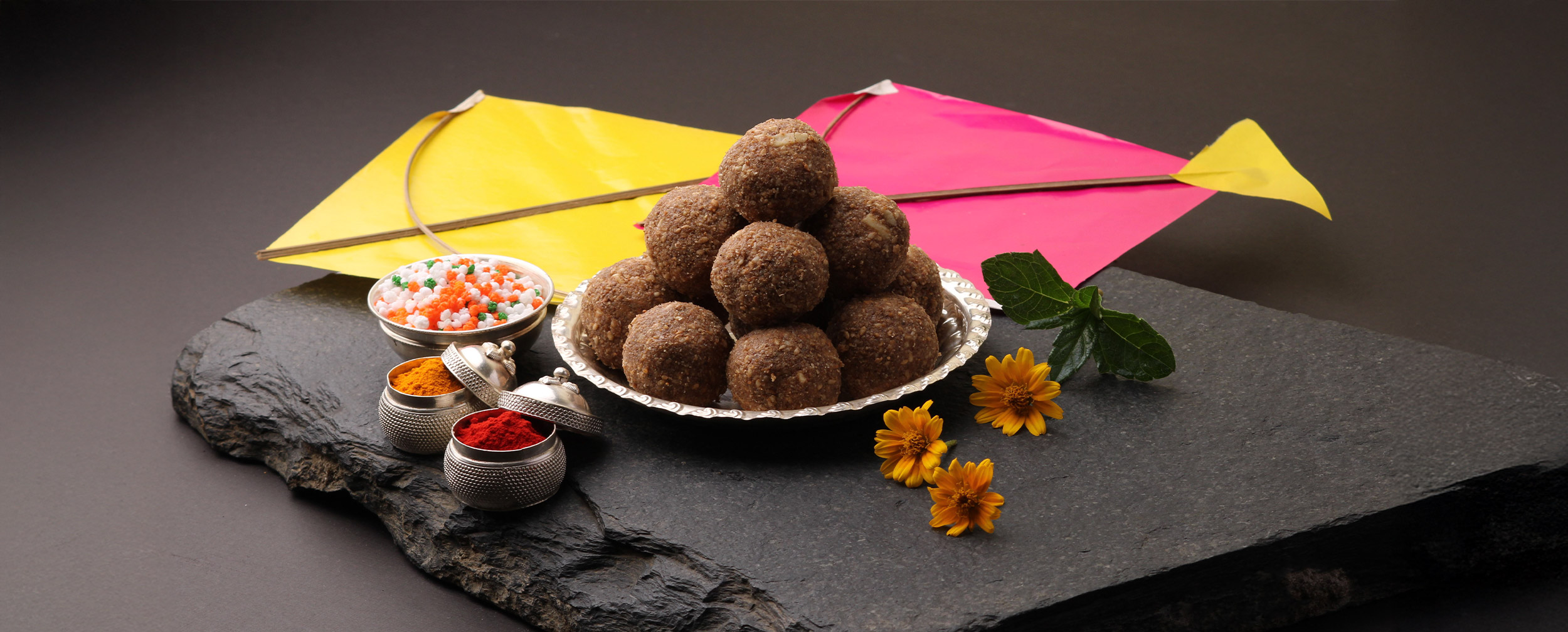 kites with traditional indian makar sankranti laddo and ti gul with yello turmeric and red sindoor with yellow flowers kites with traditional indian makar sankranti laddo and ti gul with yello turmeric and red sindoor with yellow flowers